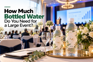 How much bottled water is needed for a large event, featuring custom-labeled water bottles at a corporate conference with a stage, audience, and elegant table setup.